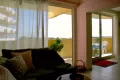Wohnbereich mit bodentiefen Fenstern, Couch und Blick auf Balkon und Meer in der privaten Ferienwohnung L’Aubergine Bellevue
